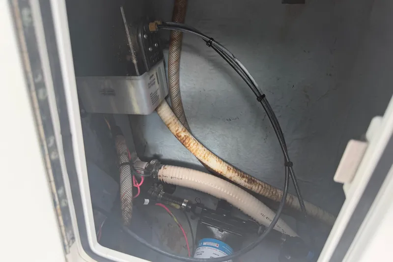 Slide: The Image of Interior view of a 1990 Mako 241 Center Console boat's compartment with hoses and wiring. - 23