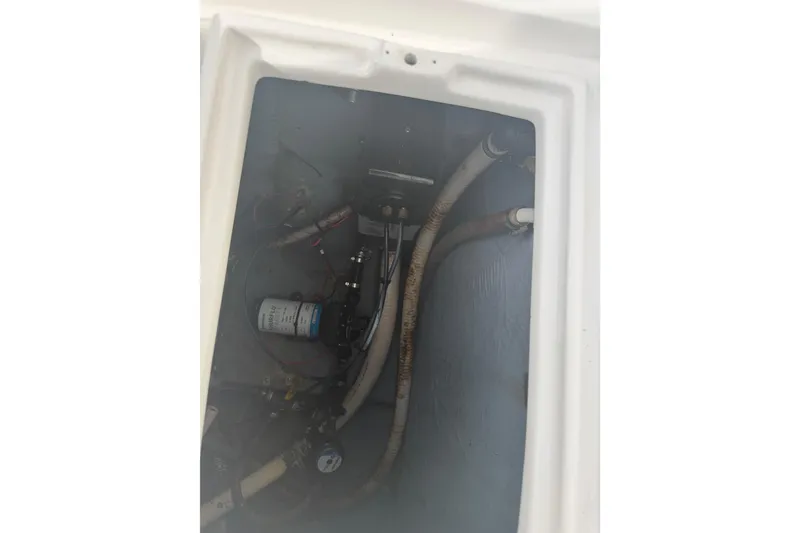 Slide: The Image of Interior view of a 1990 Mako 241 Center Console boat showing mechanical components and hoses. - 31