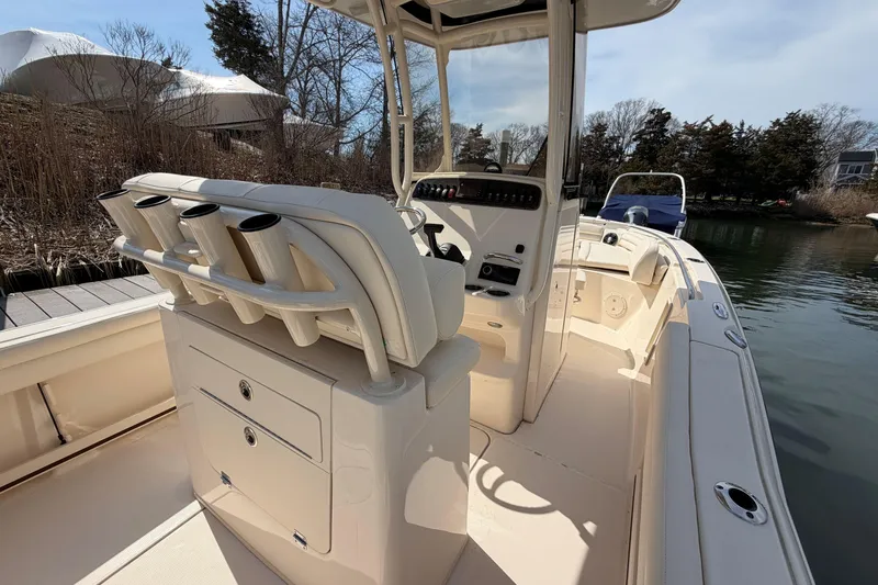 Slide: The Image of 2026 Grady-White Fisherman 216 boat interior with rod holders and console, docked by water. - 8