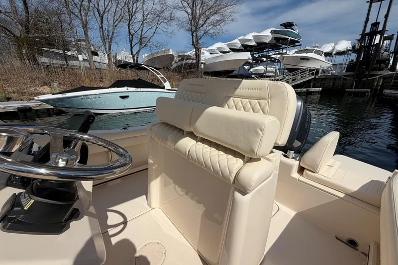 Slide: The Image of 2026 Grady-White Fisherman 216 boat interior with steering wheel and seating, docked near other boats. - 9