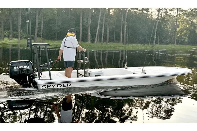 Slide: The Image of Manufacturer Provided Image: 2025 Spyder FX16 Wisp boat on calm water, featuring Suzuki outboard motor. - 2