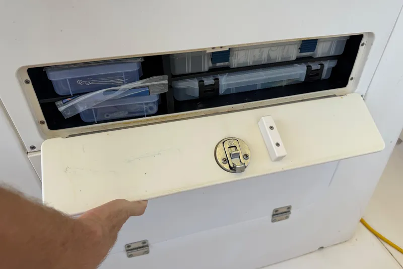 Slide: The Image of Storage compartment on a 2004 Grady-White Advance 257 boat, containing organized plastic boxes. - 19