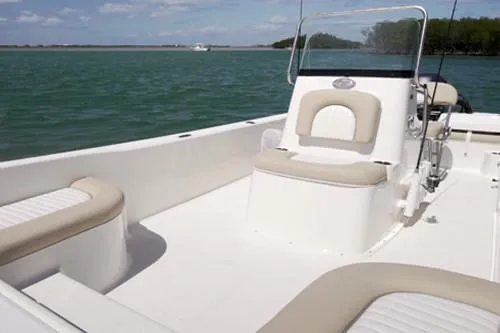 Slide: The Image of Manufacturer Provided Image: 2025 Sundance DX20 boat with beige seating, on calm water under a clear sky. - 7
