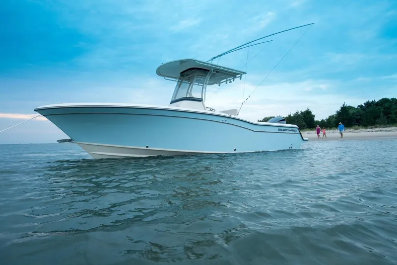 Slide: The Image of 2026 Grady-White Fisherman 236 boat anchored near a sandy beach under a blue sky. - 2
