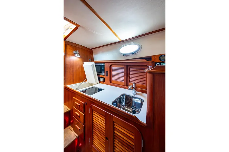 Slide: The Image of 2011 Hinckley Picnic Boat 37 MKIII interior galley with wooden cabinetry and modern appliances. - 15