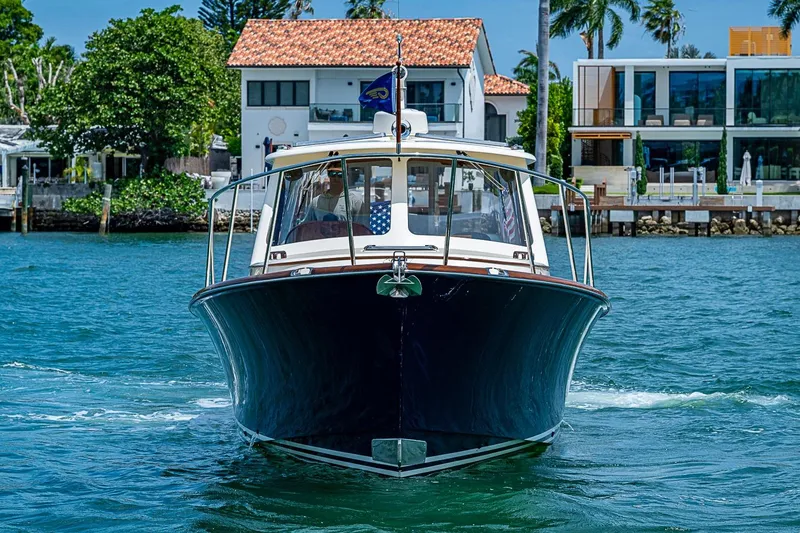 Slide: The Image of Hinckley Picnic Boat 37 MKIII cruising on water, 2011 model, with waterfront homes in background. - 2