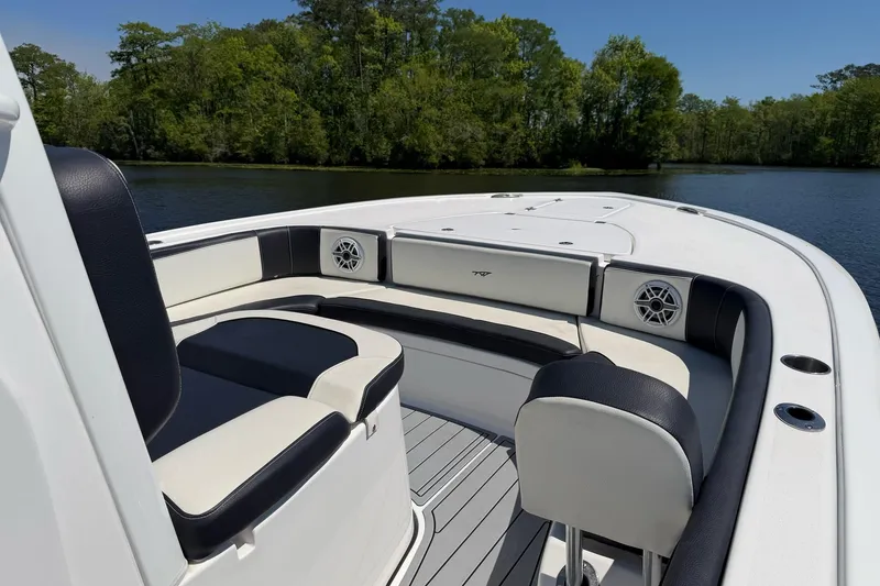 Slide: The Image of 2024 Tidewater 2700 Carolina Bay boat interior with cushioned seating and speakers, set on a serene lake. - 14