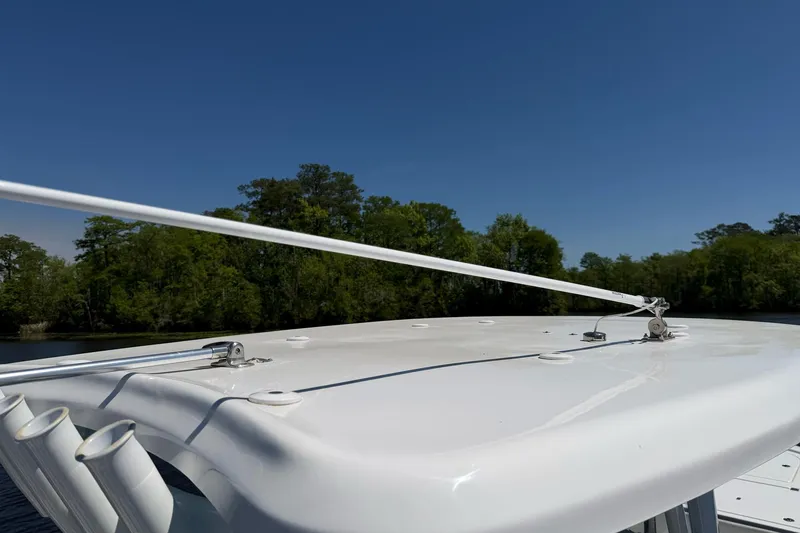 Slide: The Image of 2024 Tidewater 2700 Carolina Bay boat roof with rod holders, against a clear blue sky. - 16