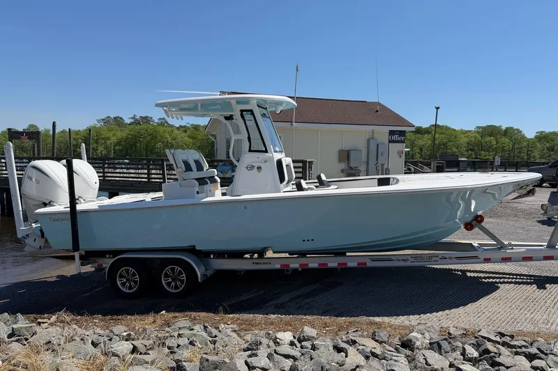 Slide: The Image of 2024 Tidewater 2700 Carolina Bay boat on trailer, parked near a marina. - 22