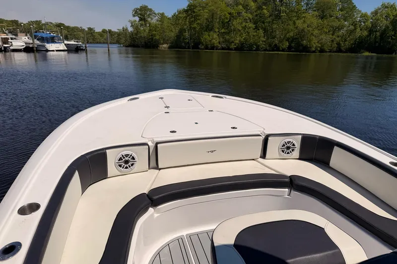 Slide: The Image of 2024 Tidewater 2700 Carolina Bay boat interior with seating and speakers on calm water. - 4