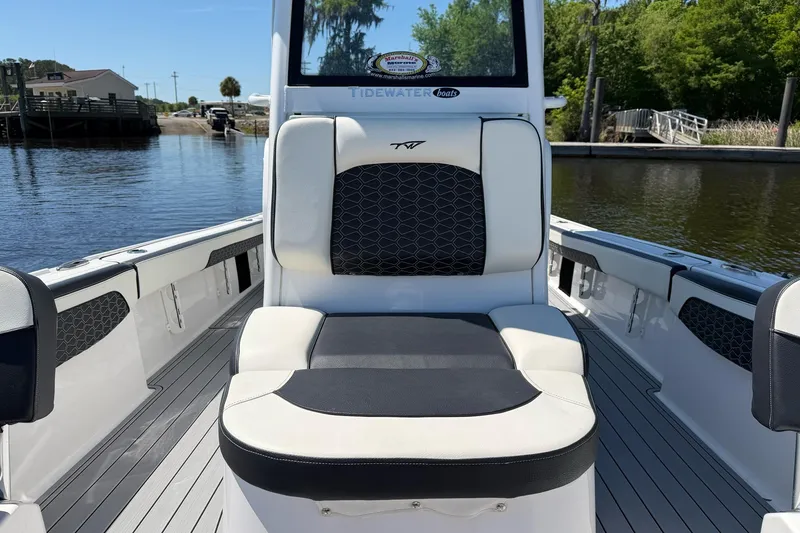 Slide: The Image of 2024 Tidewater 2700 Carolina Bay boat interior with cushioned seating, docked by a serene waterway. - 8