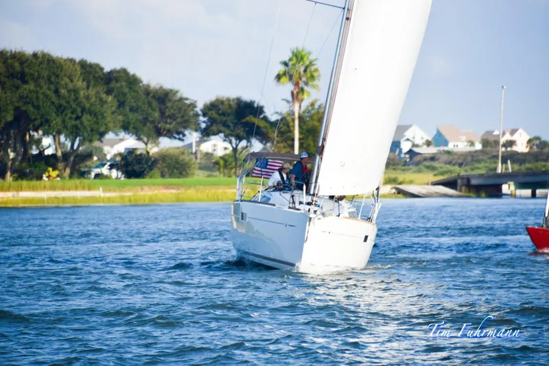 The Image of 2019 Jeanneau Sun Odyssey 349 sailing near a scenic shoreline with trees and houses. - 0