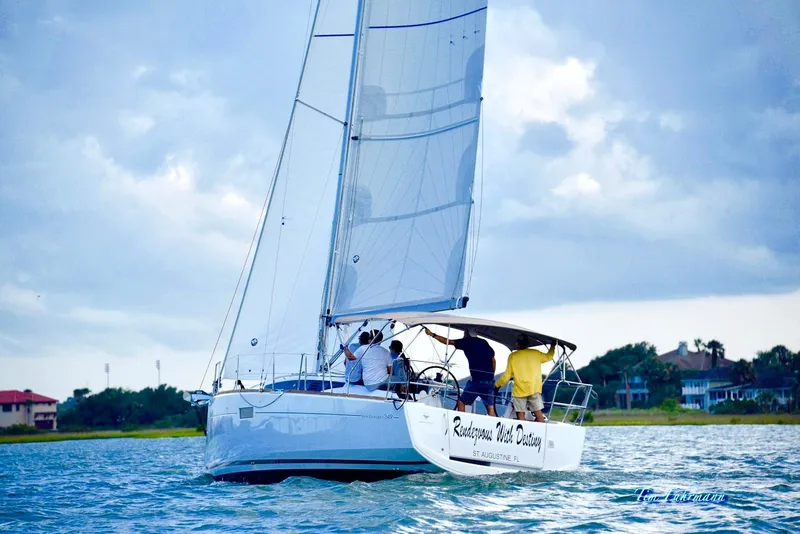 Slide: The Image of Sailing Jeanneau Sun Odyssey 349, 2019 model, on a serene waterway under cloudy skies. - 1