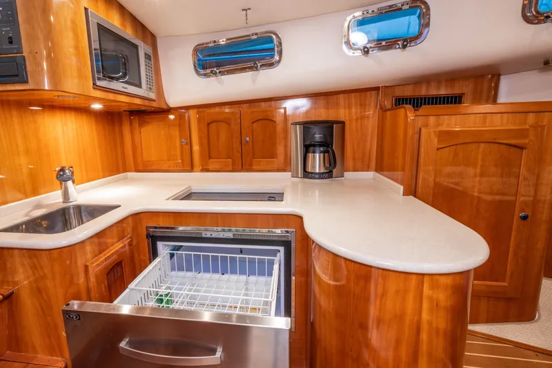 Slide: The Image of Luxurious 2007 Legacy 32 Express yacht kitchen with wood cabinetry, sink, microwave, and coffee maker. - 9