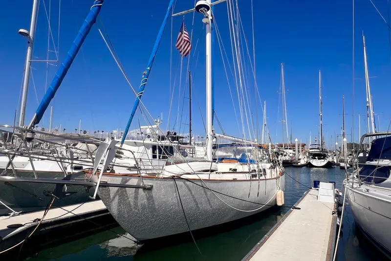 The Image of 1983 Westsail 42 Center Cockpit sailboat docked in a marina under clear blue skies. - 0