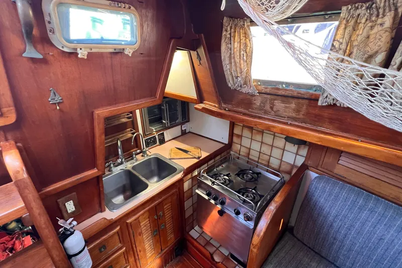 Slide: The Image of 1983 Westsail 42 Center Cockpit galley with stove, sink, and wooden cabinetry. - 25