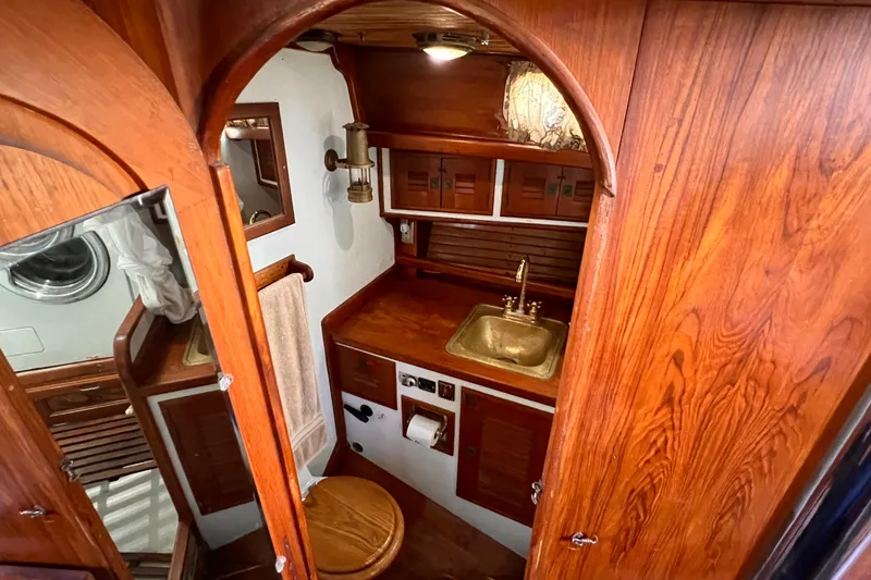 Slide: The Image of 1983 Westsail 42 Center Cockpit bathroom with wooden cabinetry and brass sink. - 33