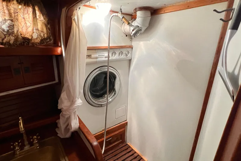 Slide: The Image of Laundry area in 1983 Westsail 42 Center Cockpit yacht with washing machine and wooden accents. - 34