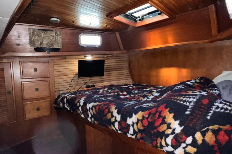 Slide: The Image of Cozy cabin interior of 1983 Westsail 42 Center Cockpit with wooden finish and patterned bedding. - 45