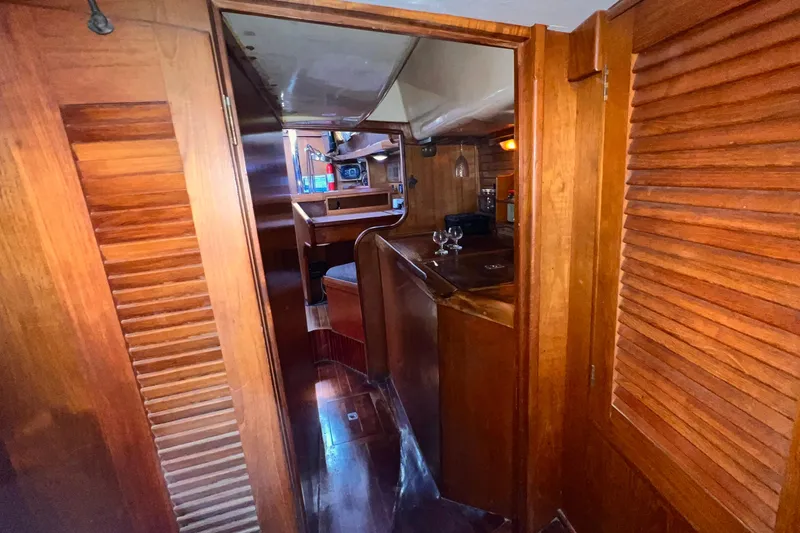 Slide: The Image of Interior of 1983 Westsail 42 Center Cockpit yacht, featuring wooden cabinetry and cozy dining area. - 46