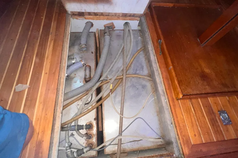 Slide: The Image of Bilge area of 1983 Westsail 42 Center Cockpit with hoses and wooden flooring. - 51