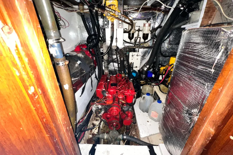 Slide: The Image of Engine room of a 1983 Westsail 42 Center Cockpit sailboat, featuring a red engine. - 62