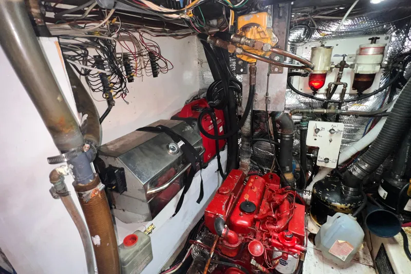 Slide: The Image of Engine room of a 1983 Westsail 42 Center Cockpit sailboat, featuring red engine and wiring. - 64