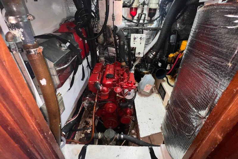 Slide: The Image of Engine room of 1983 Westsail 42 Center Cockpit sailboat, featuring a red engine and various components. - 66