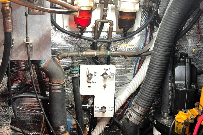 Slide: The Image of Engine room of a 1983 Westsail 42 Center Cockpit sailboat, showing fuel lines and components. - 71