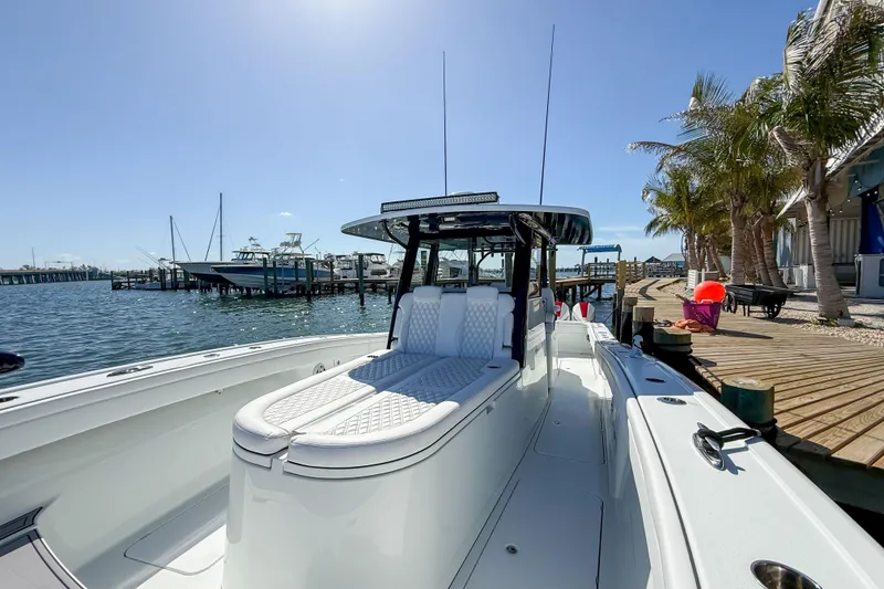 Slide: The Image of 2023 Costa Custom Boats 34 docked by palm trees, showcasing sleek design and luxury seating. - 17