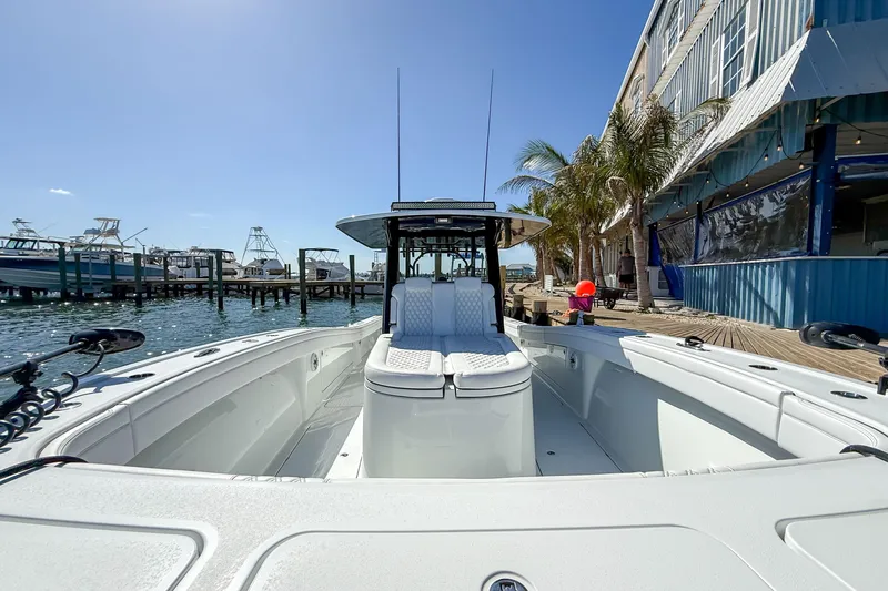Slide: The Image of 2023 Costa Custom Boats 34 docked, showcasing sleek design and spacious deck under clear blue sky. - 18