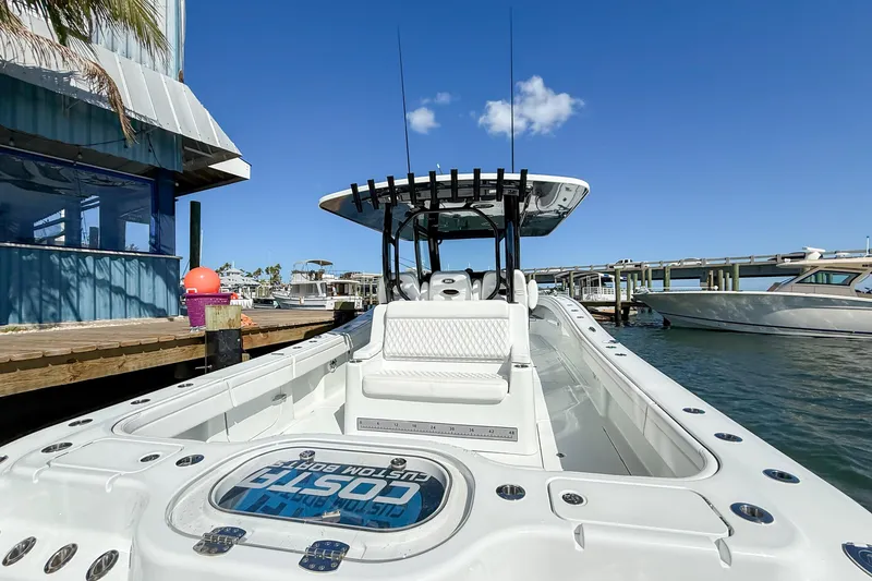 Slide: The Image of 2023 Costa Custom Boats 34 docked, showcasing sleek design and spacious deck under clear blue sky. - 25
