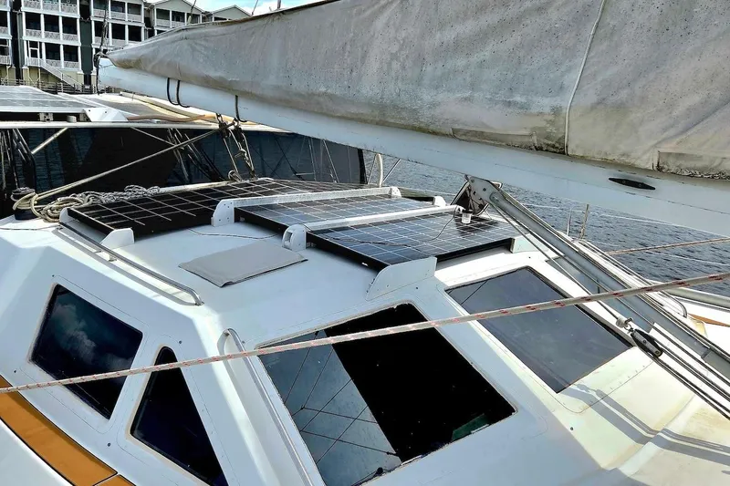 Slide: The Image of 1995 Catamaran St. Francis 43 with solar panels on deck, docked near buildings. - 13