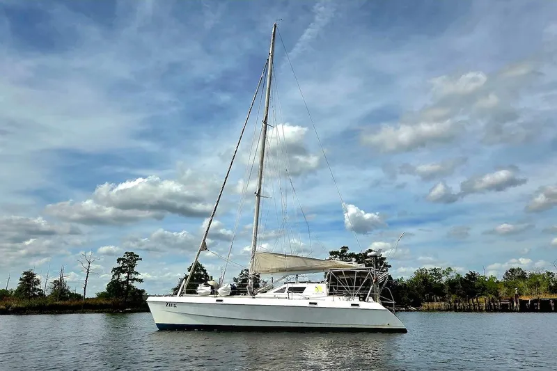 Slide: The Image of 1995 Catamaran St. Francis 43 sailing on a calm river under a partly cloudy sky. - 5