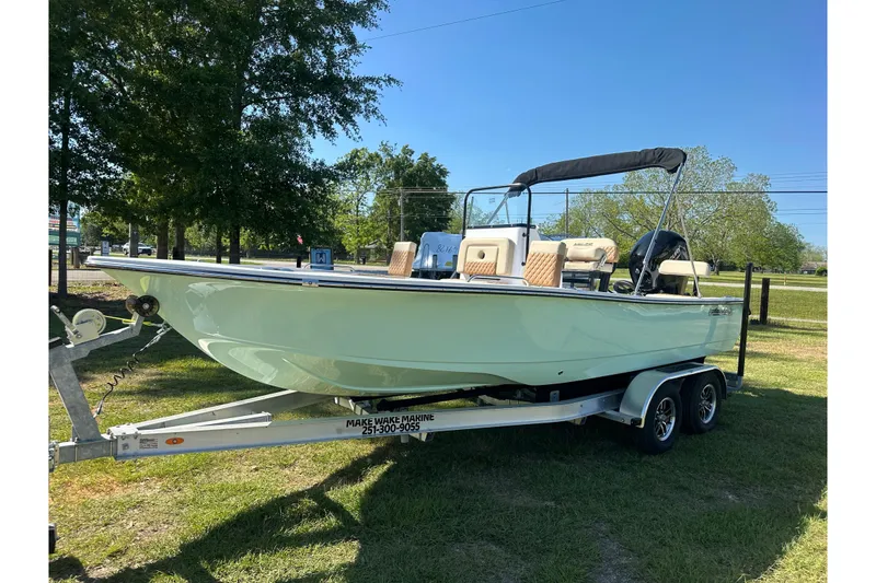 The Image of 2026 Action Craft 22 Bay boat on trailer, parked outdoors under clear blue sky. - 0