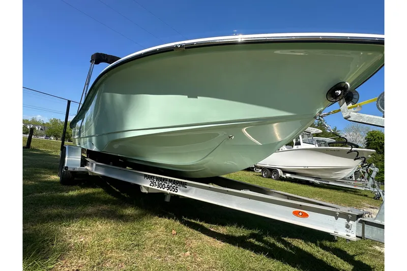 Slide: The Image of 2026 Action Craft 22 Bay boat on trailer, displayed outdoors under clear blue sky. - 11