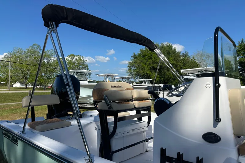 Slide: The Image of 2026 Action Craft 22 Bay boat with seating and canopy, parked outdoors under blue sky. - 45
