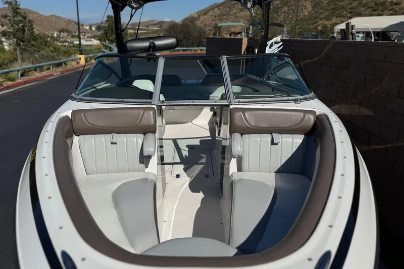 Slide: The Image of 2010 Regal 2300 RX Bowrider boat interior with seating and windshield, parked outdoors. - 15