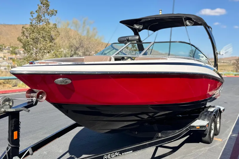 Slide: The Image of 2010 Regal 2300 RX Bowrider boat on trailer, vibrant red hull, sunny day. - 3