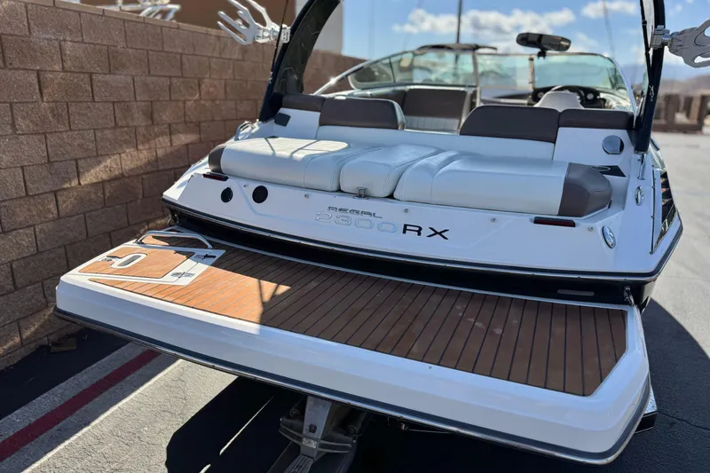Slide: The Image of 2010 Regal 2300 RX Bowrider with teak swim platform, parked near a brick wall. - 6