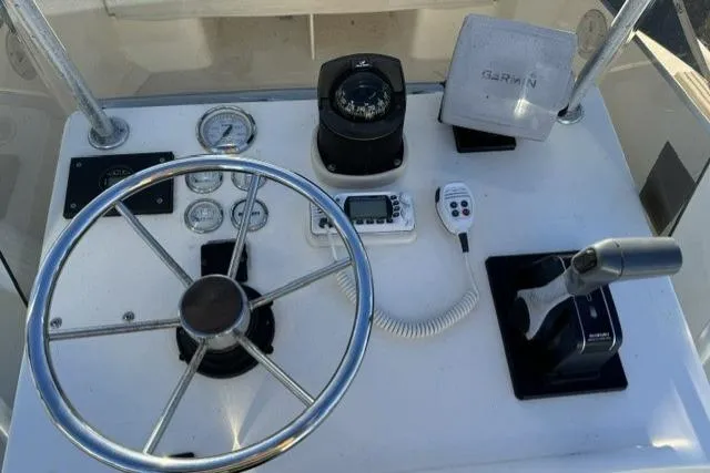 Slide: The Image of 1991 Mako 191 Inshore boat dashboard with steering wheel, compass, and Garmin device. - 8