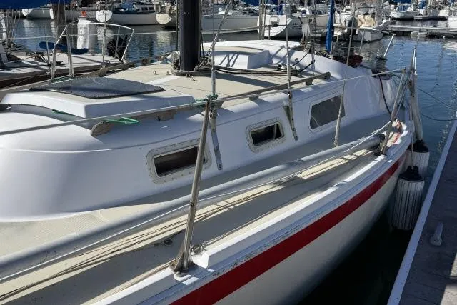 Slide: The Image of 1976 CAL 3-30 sailboat docked in marina, featuring sleek design and red stripe. - 9