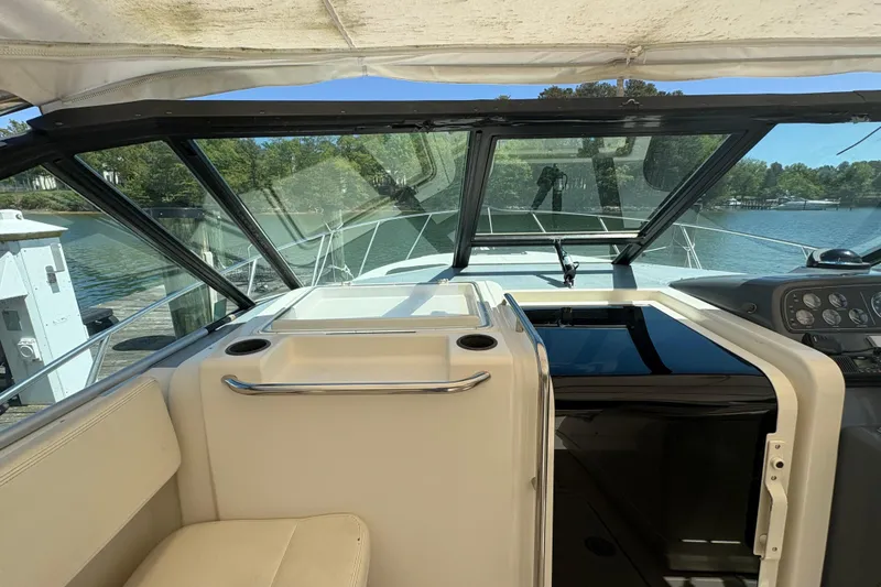 Slide: The Image of 1994 Tiara Yachts 3100 Open cockpit with helm, docked by a serene lake. - 11