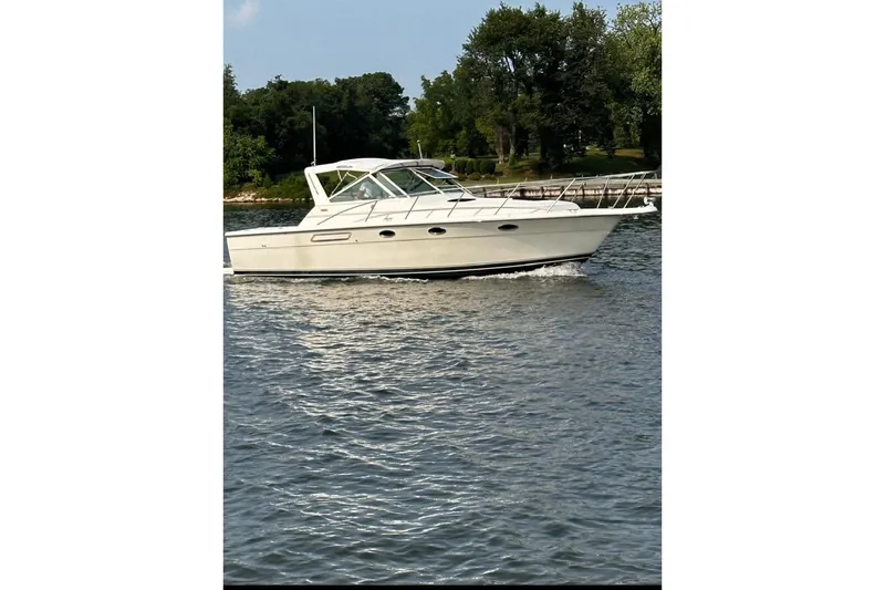 Slide: The Image of 1994 Tiara Yachts 3100 Open cruising on a calm lake with lush greenery. - 14
