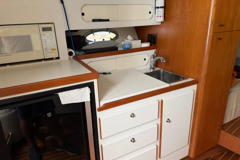 Slide: The Image of 1994 Tiara Yachts 3100 Open galley with sink, microwave, and storage cabinets. - 8