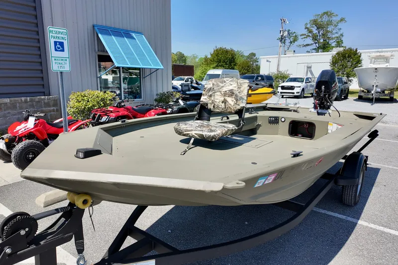 Slide: The Image of 2025 TRACKER BOATS 1654 MVX Sportsman on trailer, parked outdoors near ATVs. - 11
