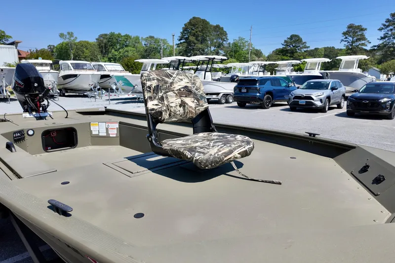 Slide: The Image of 2025 TRACKER BOATS 1654 MVX Sportsman with camouflage seat in a boatyard. - 9