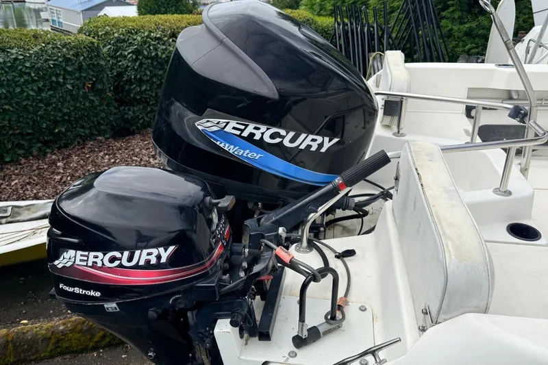Slide: The Image of 1999 Boston Whaler Outrage 18 with dual Mercury outboard motors, docked outdoors. - 10