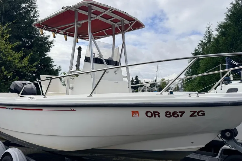 Slide: The Image of 1999 Boston Whaler Outrage 18 boat with red canopy, docked outdoors. - 3