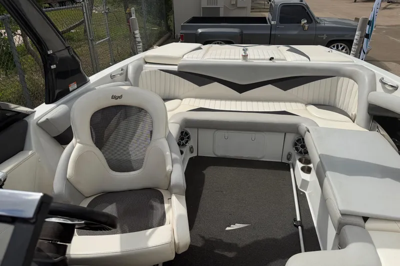 Slide: The Image of 2010 Tigé RZ2 boat interior with white seating and steering wheel, parked near a fence. - 18